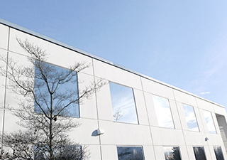 White In2Net Network Facility Building Exterior with Tree in the Foreground and Blue Sky Background