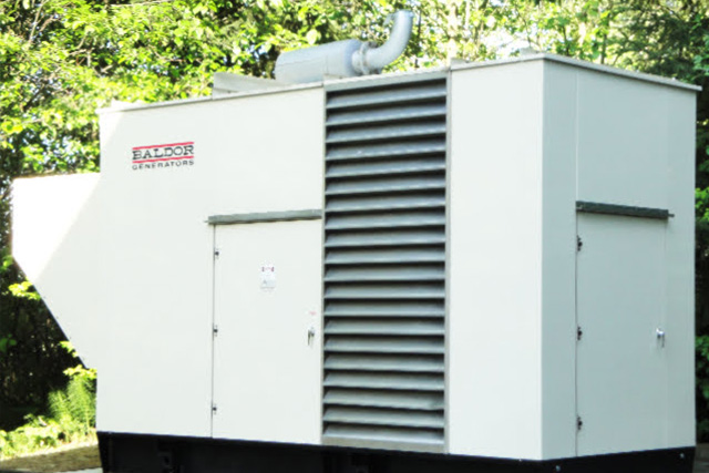 White Baldor 450KW Outdoor Power Generator with Green Maple Leaves in the Background
